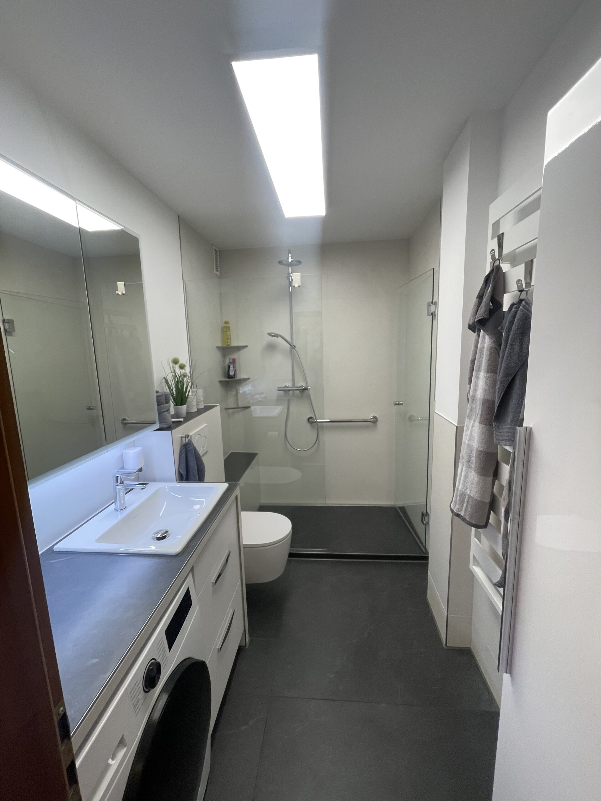 Lange Aquanau Duschrinne nach Maß entlang der Rückwand einer großzügigen Dusche